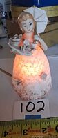 Front view of illuminated porcelain lady night-light holding parasol showing glow and overall design