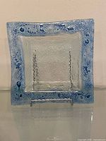 Front view of clear fused glass square dish with blue bubble accents