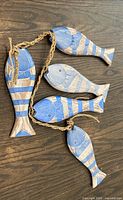 Five carved wooden fish connected by jute rope on wooden surface
