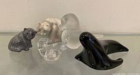 group of five animal figurines on glass shelf
