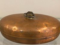 Top view of copper bed warmer showing brass ring handle and patina