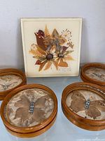 Front view of four round coasters and square tile with pressed botanicals