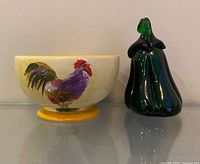Side view of rooster bowl and glass eggplant