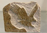 Front of stone slab showing carved eagle relief and artist marking