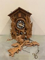Front view of carved wooden cuckoo clock showing overall design, missing weights