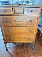 Full front view of dresser showing six drawers, hardware, legs, finish wear