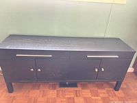 Front view of black sideboard showing overall design, drawers, doors, and legs