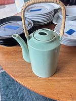 Full view of celadon teapot on table showing body, spout, lid, and handle