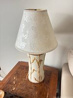 Full view of ceramic table lamp with shade on wooden side table