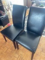 Full view of both black armless dining chairs standing together