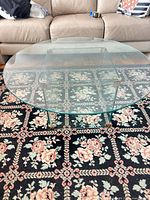 full view of round glass coffee table on floral rug