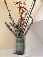Full view of green ceramic vase with faux red orchids, eucalyptus and greenery