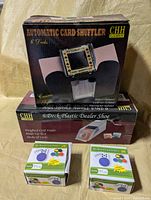 Box of CHH Games automatic card shuffler atop dealer shoe box with two card holder boxes in front