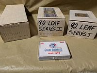 Three factory card set boxes and one plastic card case showing labels