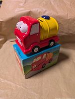 Front three-quarter view of ceramic truck coin bank on top of its box