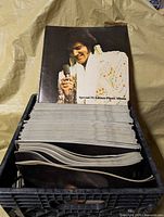 Front view of booklet showing Elvis on cover and stack inside milk crate