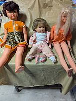 Group shot of three large dolls seated with bag of three small dolls on lap