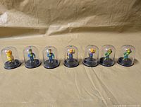 All eight Simpsons mini figures in domes lined up