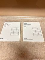 Two unopened packs of Baseline mailing labels on countertop
