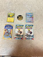 Overview of all six items laid out: two Pokémon fun packs, Lorcana booster, Pikachu card, Glaceon V card, Pikachu coin