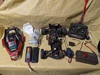 Overall lot showing chassis, body shell, transmitter, secondary controller, battery packs and parts