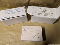 Three white storage boxes labeled with set details