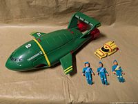 Group shot showing Thunderbird 2, yellow auxiliary craft and three figures
