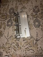 Top view of GBC silver metal punch machine showing three adjustable punch heads and ruler scale