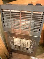 Front view of gray metal propane wall heater showing louvered vent and ceramic element