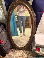 Front view of oval mirror leaning against wall