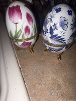 Front view of both porcelain trinket eggs showing patterns and gold-tone hinge