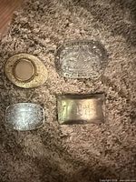 Overall view of four belt buckles on rug