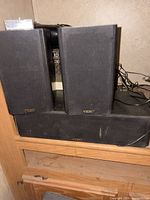 Front view of three TEAC speakers showing two satellites stacked on center channel, cabling visible