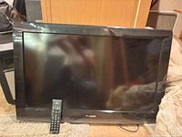 Front view of Toshiba 32-inch flat screen TV with remote placed against screen