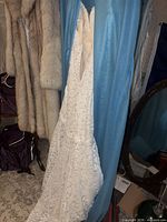 Full view of white lace wedding dress hanging, showing mermaid silhouette and lace texture