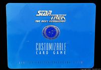 Front of blue metal collector’s tin with Star Trek TNG CCG graphics