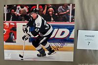 Full photo showing Fredrik Modin skating, autograph visible, size reference slip adjacent