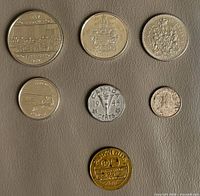 Obverse sides of six coins and transit token arranged on surface