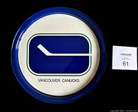 Front of plate showing Canucks stick-in-rink logo and blue rim