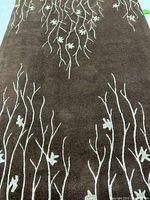 Full view of brown rug with beige branch motif