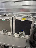 Two carpeted flight cases side by side showing fronts, latches, numbers 10 and 15