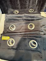 Folded black curtain panels showing silver grommets
