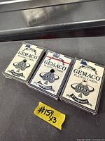 Front view of three Gemaco playing card decks in boxes, one sealed, two opened