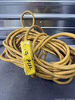 Coiled yellow extension cord showing length tag and molded ends