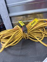 Coiled yellow 50-ft extension cord with three-prong plug