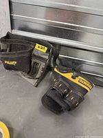 DeWalt and AWP tool belt pouches on floor