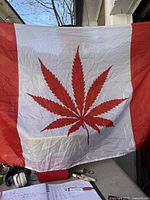 Full view of red and white flag with cannabis leaf motif hanging, showing design and grommets