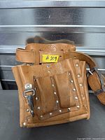 Front view of tan leather tool belt with riveted pouch and belt buckle visible