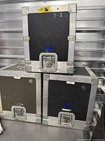 Stacked view of three black flight cases showing latch hardware and condition