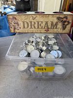 Plastic bin filled with many tea light candles and wooden triple tea light holder placed on top